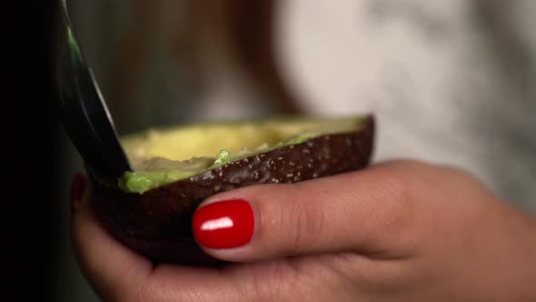 Woman Takes Out the Pulp of the Avocado From the Peel with a Spoon.