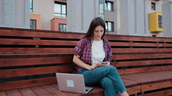 Girl Student Skateboarder Rejoices at the Unexpected Win on the Internet on Her Laptop in the Park