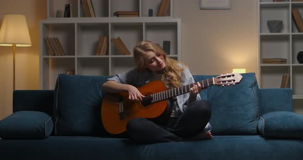 Spending Evening Alone at Home Young Woman Is Playing Guitar and Enjoying Music Plucking Strings alt