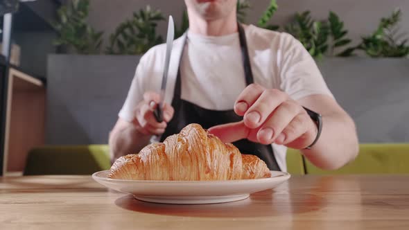 Baker Cuts Fresh Crispy Croissant and Shows the Chocolate Filling Close Up alt
