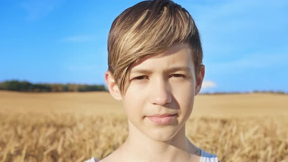 Portrait of a Boy with a Stylish Hairstyle Looking at the Camera and Smiling at the Wheat Field