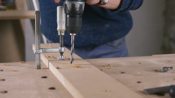 Young Man Piercing a Hole Through a Wooden Plank alt