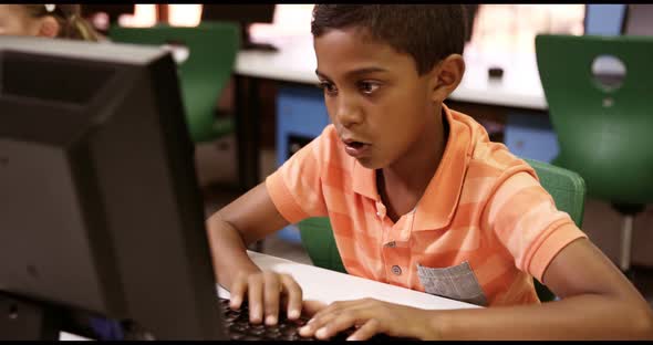 Schoolboy studying on personal computer in classroom alt
