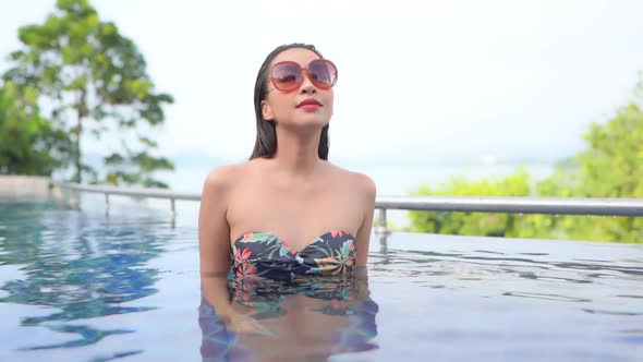 Young asian woman enjoy around outdoor swimming pool for leisure alt