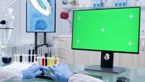 Chemist in Protective Gloves Works on Computer with Green Screen alt