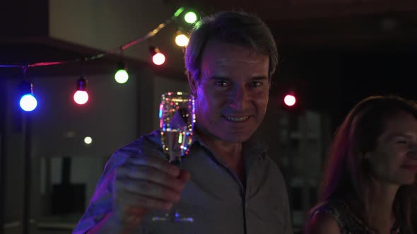 Mature man toasting with glass of champagne, viewed from personal perspective alt