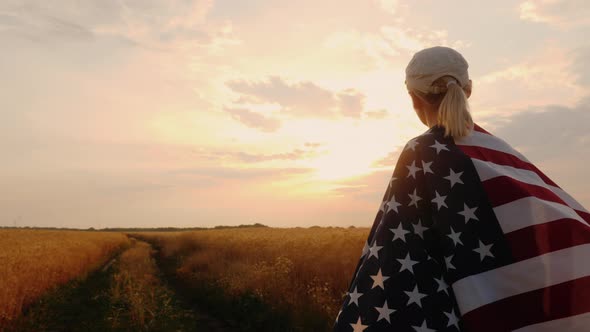 Farmer with USA Flag Walking on a Wheat Field Sun at Sunset alt
