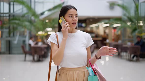 Female Shopaholic Talking with Friend on Mobile Phone About Clothes She Found During Shopping alt
