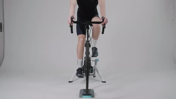 Front View of a Cyclist Training on an Exercise Bike in Bright White Studio