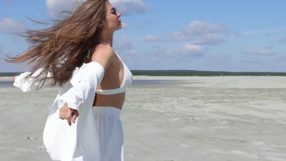 Charming Woman Standing on Beach on Windy Day