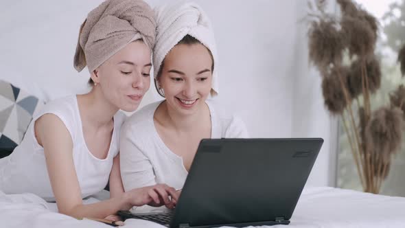 Two Girls Sitting at Home and Using Laptop alt