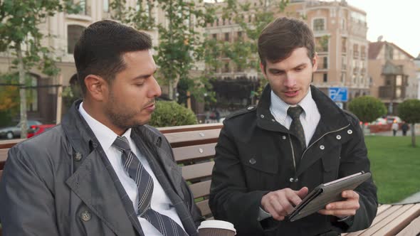 Two Men Discuss the Information They See on the Tablet alt