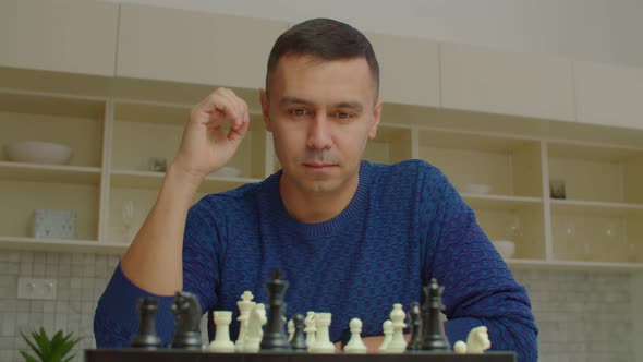 Serious Male Chess Player Moving Chess Queen and Checkmate Opponent Indoors alt