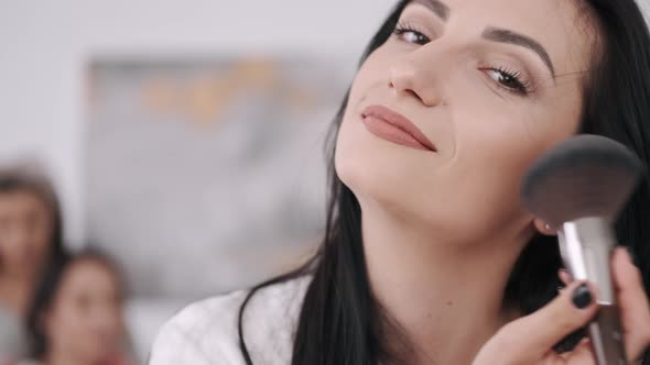 A Close View of a Beautiful Woman Doing Her Make-up and Two Girls Behind alt