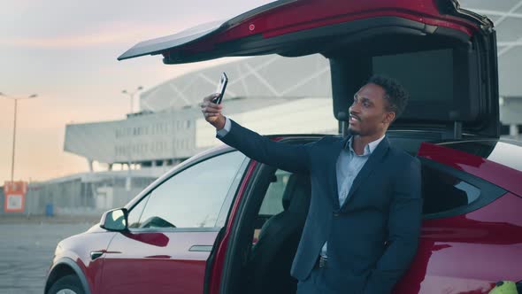 Portrait Of A Businessman Blogger At The Charging Station Of The Electric Car alt