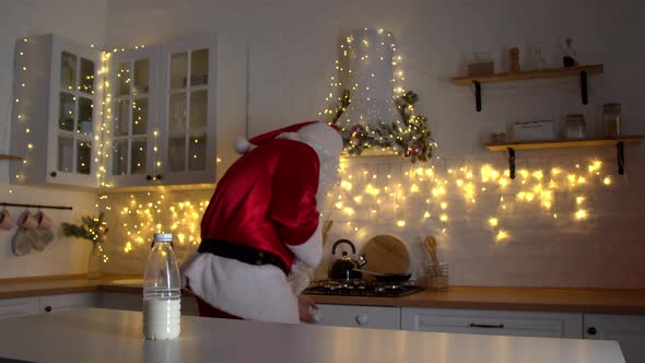 Cheerful Santa Claus Dancing in Kitchen at Christmas