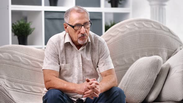 Upset 70s Grandfather Thinking About Solitude or Problem Sitting on Couch alt