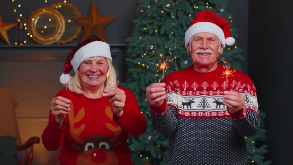 Senior Family Couple in Festive Sweaters Holding Bengal Lights Enjoying Christmas Eve at Home Room alt
