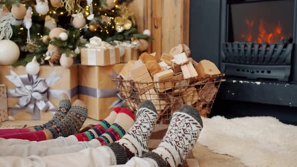 Close-up of Feet in Socks Indoors in Cozy Apartment with Fireplace and Decorated Tree alt