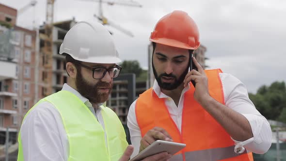 Engineer Speaks on Mobile Phone on Construction Site and Checks the Work of the Worker Builder alt
