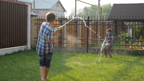 Boys in Checkered Shirts and Shorts Play with Water Guns alt