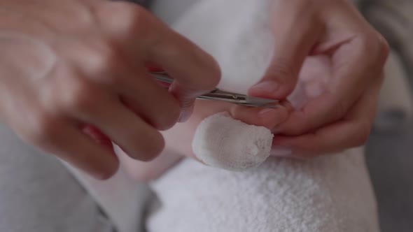 Mother Bandages Her Child's Big Toe and Cuts Nails on Other Foot alt