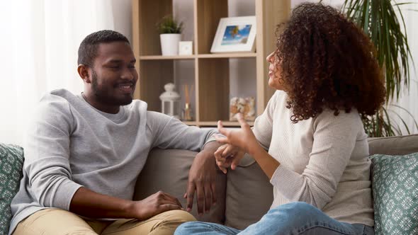 Happy Couple Sitting on Sofa and Talking at Home alt