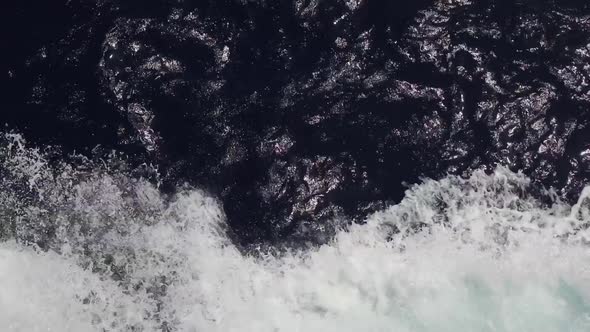 Powerful waves pulled out from fast moving boat, a huge stream of deep blue water with white foam 