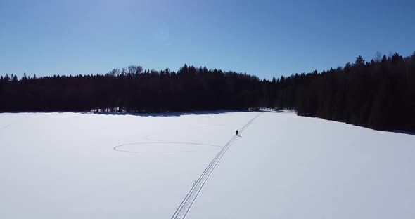 Flying Over Frozen Lake While a Woman is Walking Beneath alt