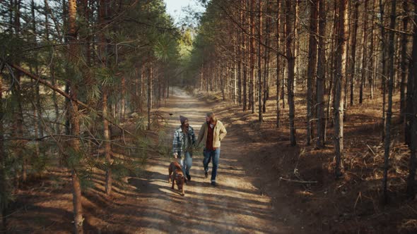 Couple and Dog Walking in Forest on Spring Day alt