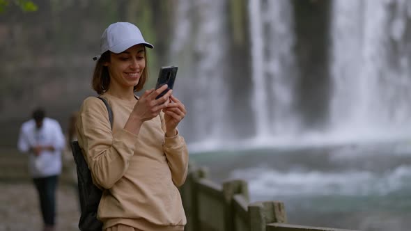 Attractive Smiling Woman Tourist Making Selfie on Mobile Phone on Lower Duden Waterfall Background alt