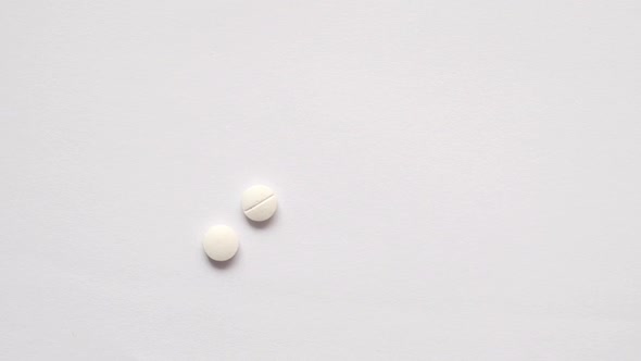 Slow Motion of White Color Medical Pills Drop on Table alt