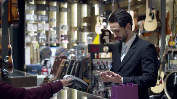 Young handsome man using and paying with smartphone contactless
