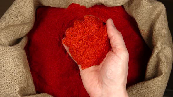  Male hand taking a handful of a red pepper powder in a sac