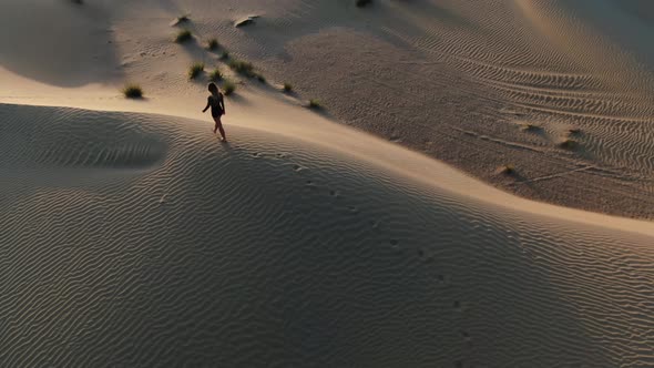 Aerial Footage of a Young Lady Walking in the Desert on a Sand Dune UAE alt