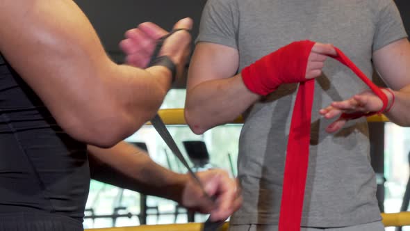 Cropped Shot of Two Male Boxers Wrapping Fists in Bandages Before Fighting alt