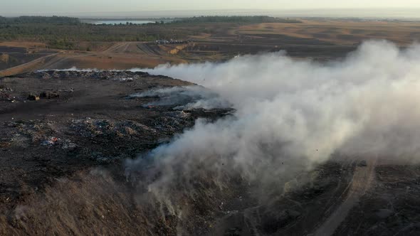 Aerial view of burning garbage pile in trash dump or landfill alt