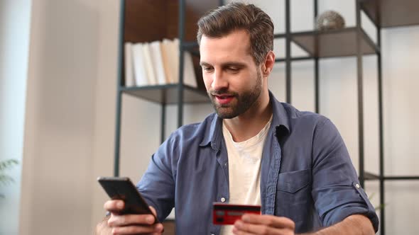 Young Bearded Hipster Guy in Casual Wear Using Mobile Phone and Credit Card alt