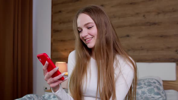 Girl Looks at Screen of Mobile Smartphone Makes Successful Online Order Smiles and Looks at Camera alt