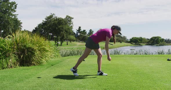 Caucasian woman playing golf putting a ball on a ground alt