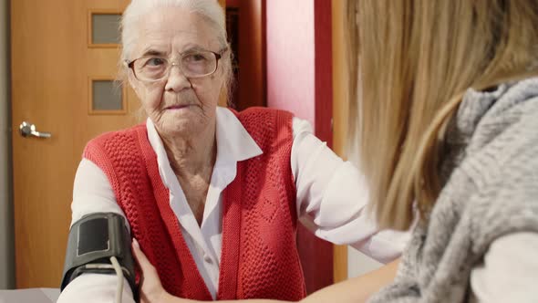 Woman Measuring Blood Pressure of Senior Grandmother