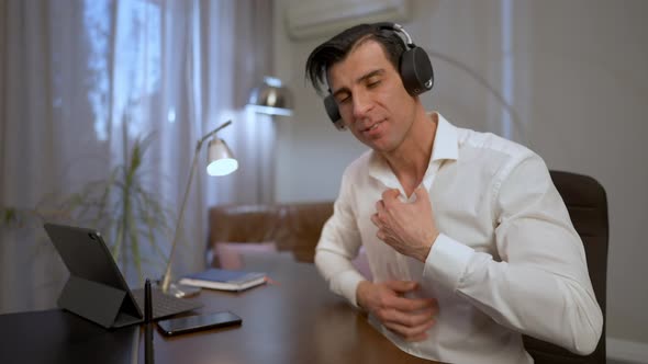 Young Middle Eastern Man Putting on Headphones and Turning on Webcamera Sitting in Home Office alt