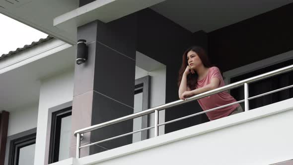 stressed woman quarantine in balcony of her home with falling rain, coronavirus pandemic concept