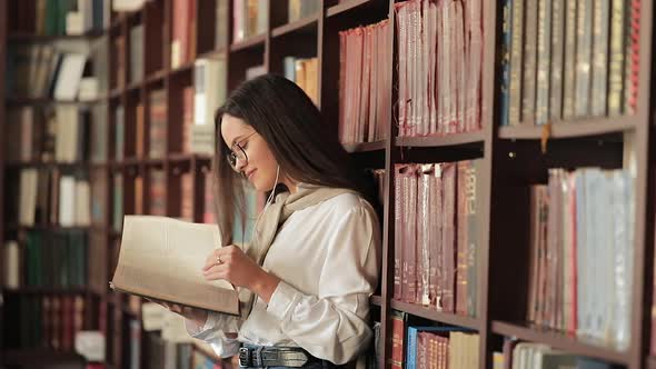 Girl Reading Book Near Bookshelf alt