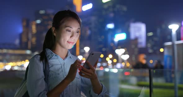 Woman look at mobile phone in city at night in Hong Kong alt