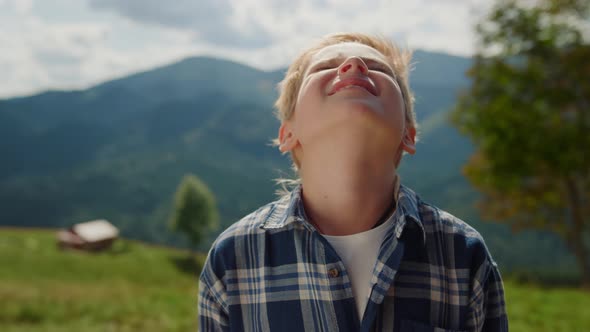 Little Boy Enjoying Sunlight Raising Head to Sky in Summer Mountains Close Up alt