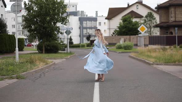 Beautiful Blonde Woman in Dress Dancing on Road.