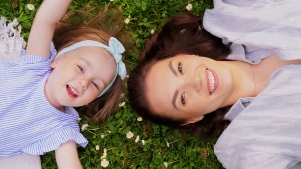 Happy Mother with Baby Girl Lying on Grass in Park