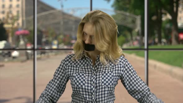 Angry Woman with Taped Mouth Looking at Camera alt