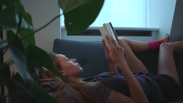 Woman Reading Book On Sofa